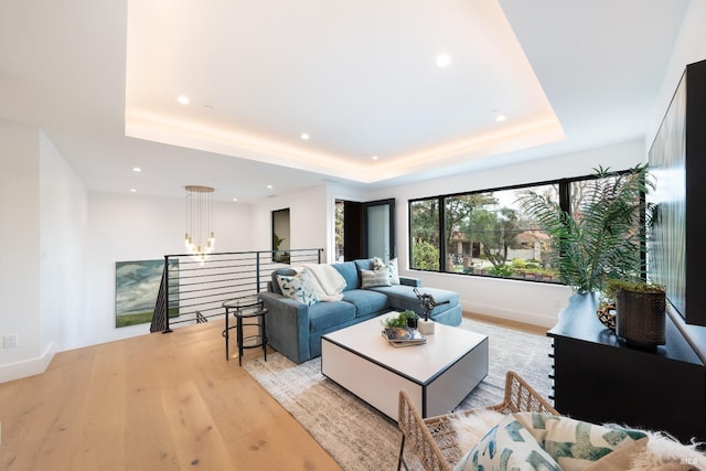 living room with light hardwood / wood-style floors and a raised ceiling