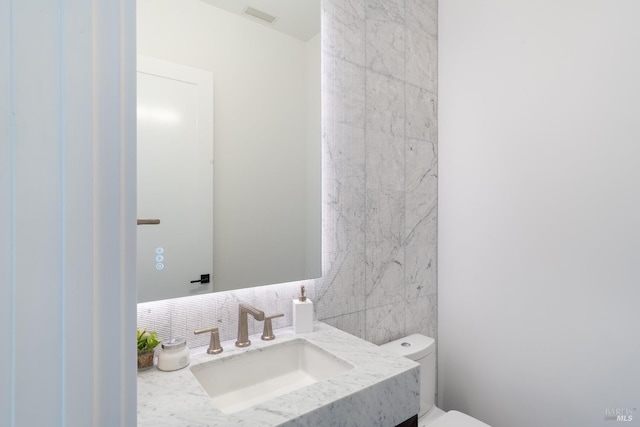 bathroom with vanity, toilet, backsplash, and tile walls