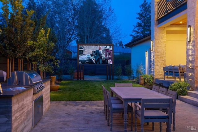 view of patio featuring grilling area, a balcony, and an outdoor kitchen