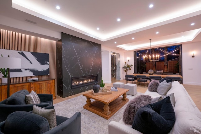 cinema room featuring an inviting chandelier, a fireplace, and a tray ceiling