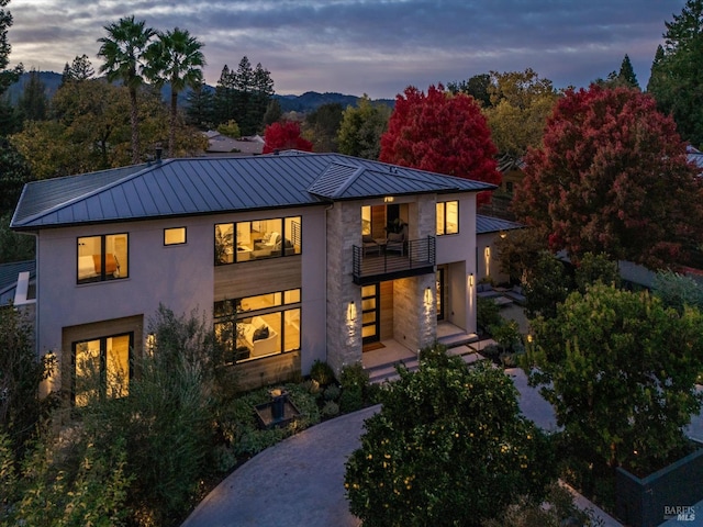 back house at dusk featuring a balcony