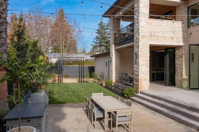 view of patio featuring a pergola, a balcony, and exterior kitchen