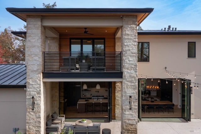 rear view of property with ceiling fan and a balcony