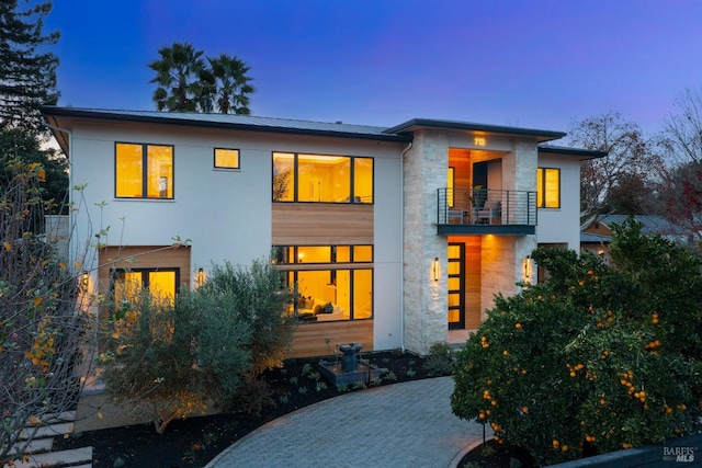 back house at dusk featuring a balcony