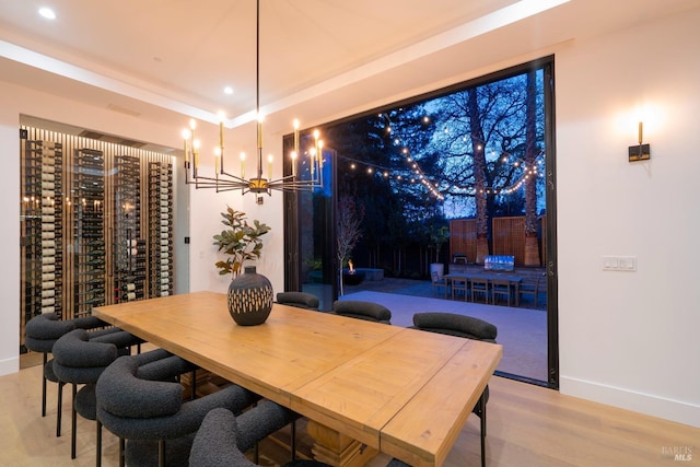 dining room featuring a raised ceiling, an inviting chandelier, and light wood-type flooring