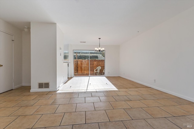 empty room with light tile patterned floors and a notable chandelier