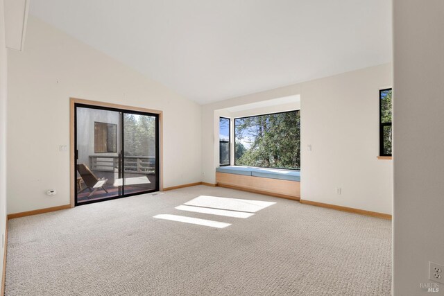 carpeted spare room featuring vaulted ceiling and plenty of natural light