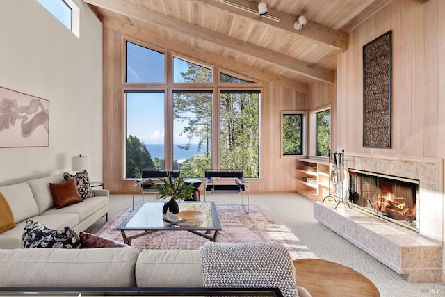 living room with carpet flooring, wood ceiling, a fireplace, vaulted ceiling with beams, and wood walls