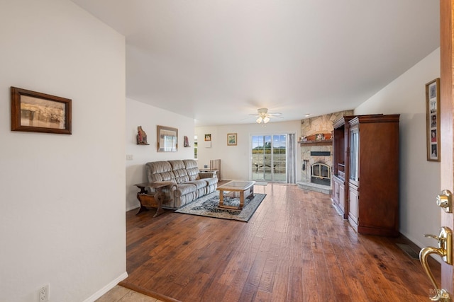 living room featuring ceiling fan, a fireplace, and wood-type flooring