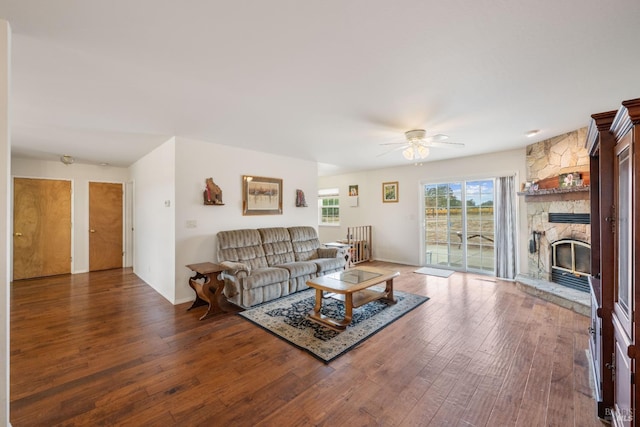 living room with dark hardwood / wood-style flooring, a fireplace, and ceiling fan