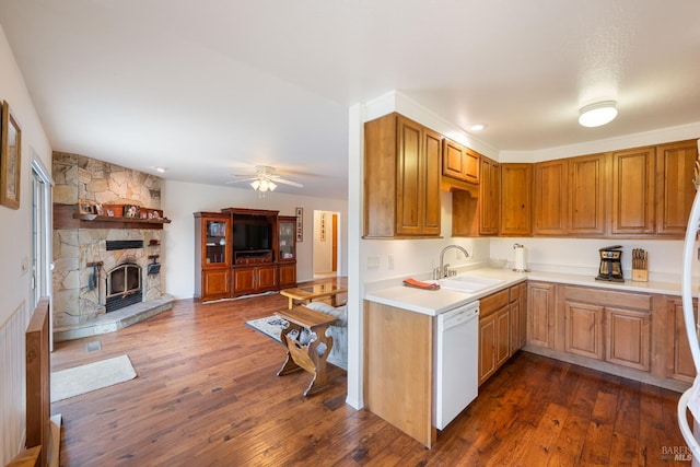 kitchen with sink, ceiling fan, dark hardwood / wood-style floors, white dishwasher, and a fireplace