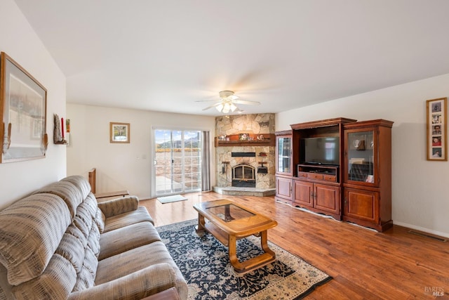 living room with hardwood / wood-style flooring, ceiling fan, and a fireplace