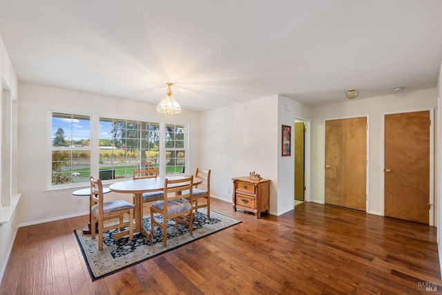 dining space featuring dark wood-type flooring, a wealth of natural light, and an inviting chandelier