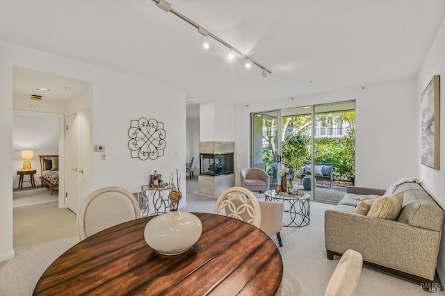 dining area featuring a tiled fireplace, light carpet, and track lighting