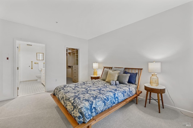 carpeted bedroom featuring a closet, a spacious closet, and ensuite bath