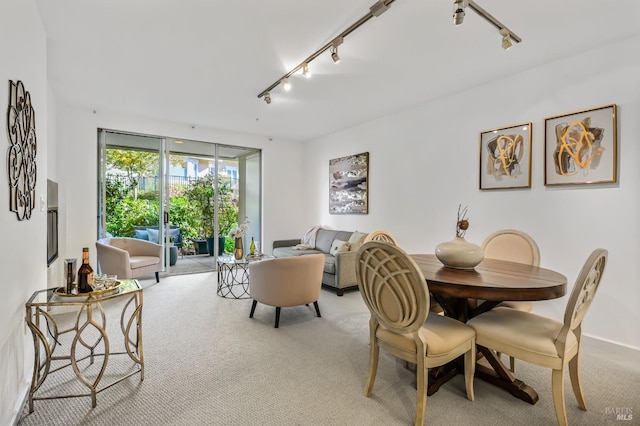 carpeted dining space featuring rail lighting