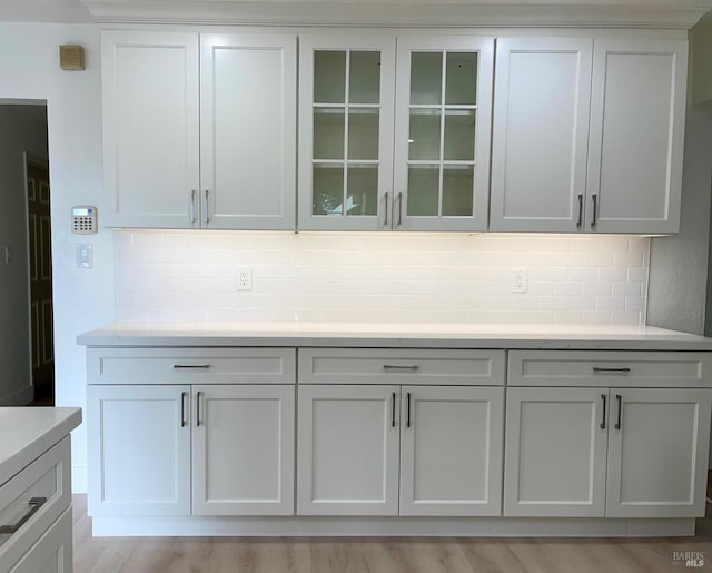 bar with light wood-type flooring, white cabinets, and tasteful backsplash