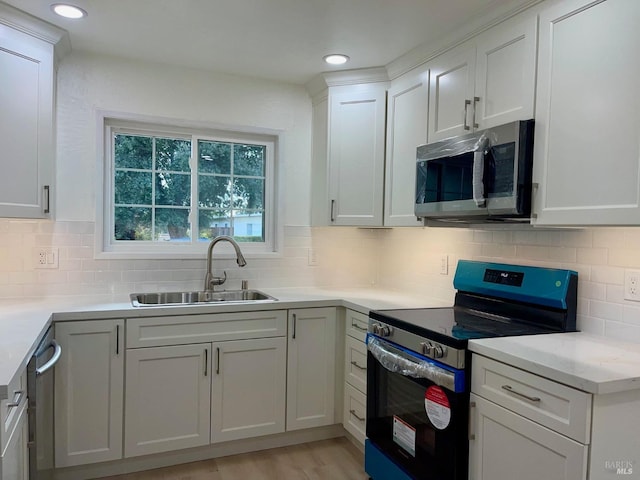 kitchen featuring backsplash, appliances with stainless steel finishes, sink, and white cabinetry