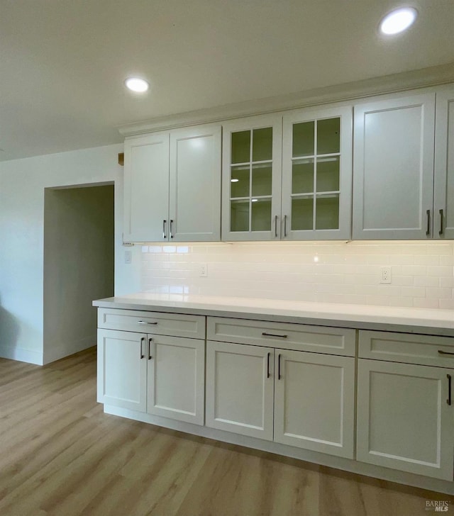 kitchen featuring decorative backsplash, light hardwood / wood-style flooring, and white cabinets