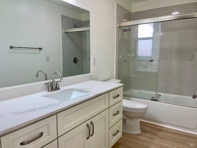 full bathroom with toilet, vanity, shower / bath combination with glass door, and hardwood / wood-style floors