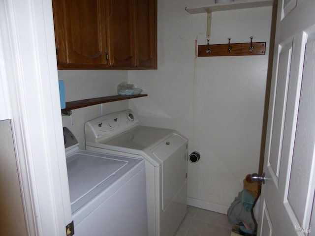 clothes washing area featuring cabinets, light tile patterned flooring, and washer and dryer