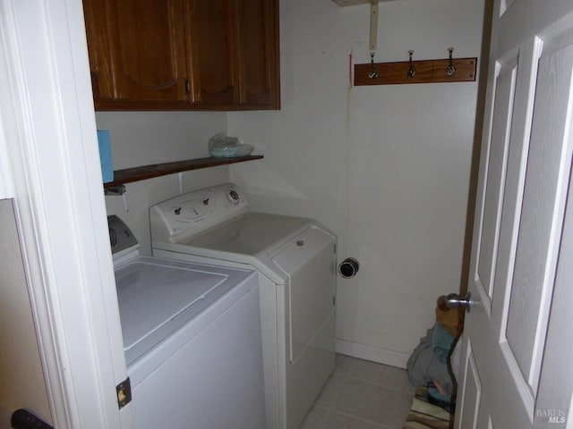 washroom featuring light tile patterned flooring, cabinets, and washing machine and clothes dryer