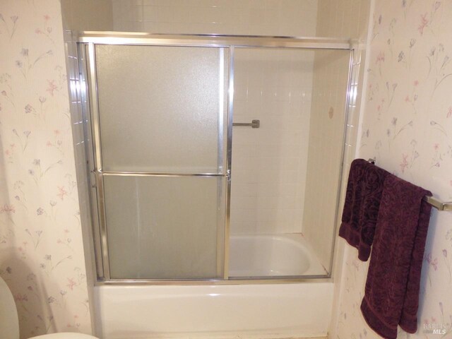 bathroom with enclosed tub / shower combo and toilet