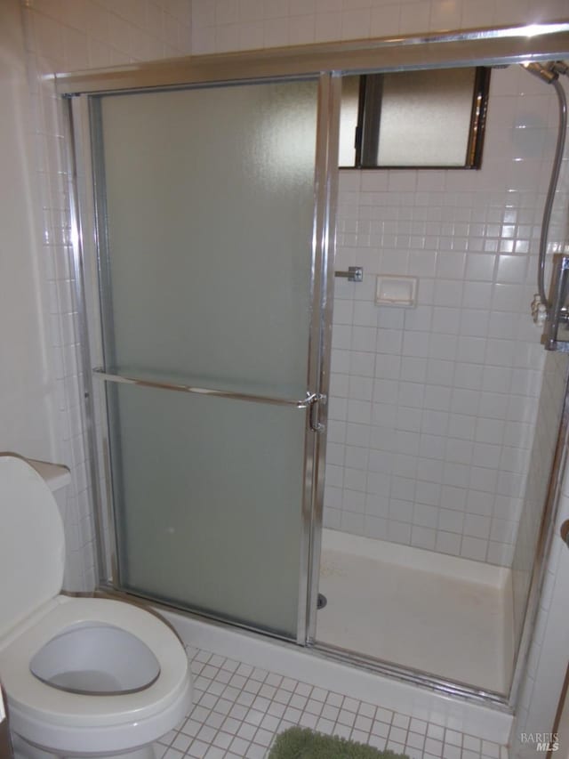 bathroom with tile patterned flooring, toilet, and an enclosed shower