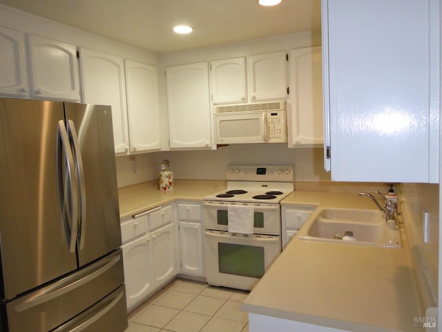 kitchen with white cabinets, light tile patterned flooring, white appliances, and sink