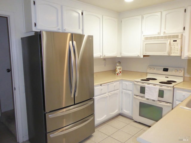 kitchen with white cabinets, light tile patterned floors, and white appliances