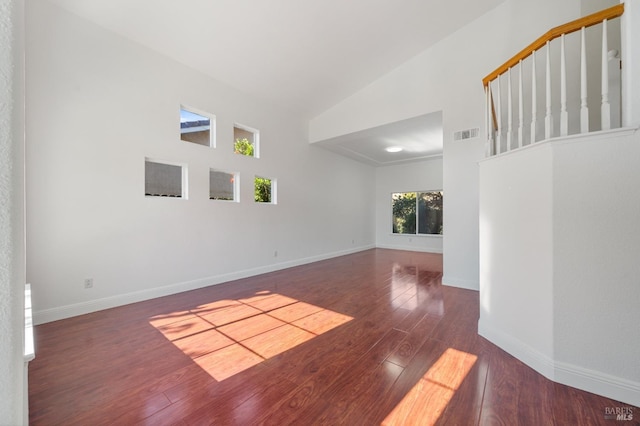 spare room with dark wood-type flooring and high vaulted ceiling