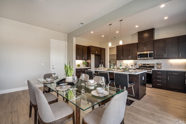 dining room featuring baseboards, light wood-type flooring, visible vents, and recessed lighting