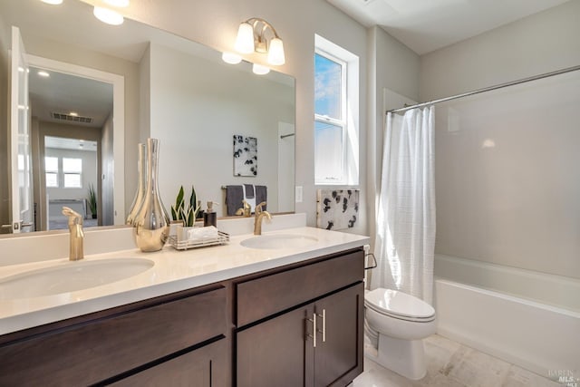 bathroom with visible vents, a sink, toilet, and double vanity