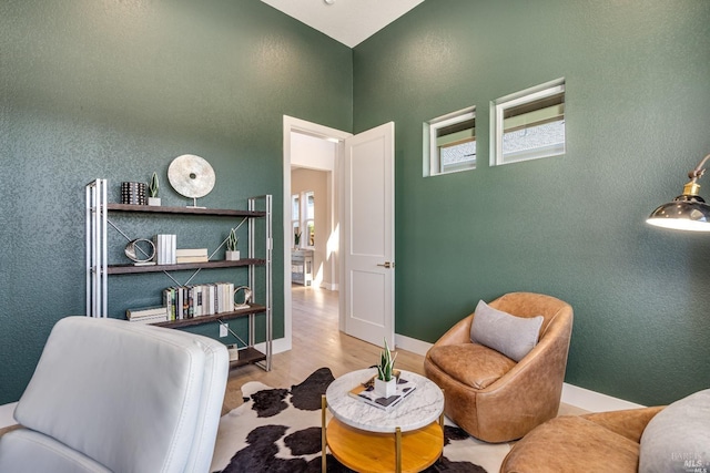 living area featuring baseboards, wood finished floors, and a textured wall