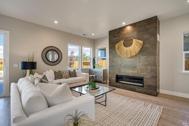 living room featuring light wood-type flooring and a tiled fireplace