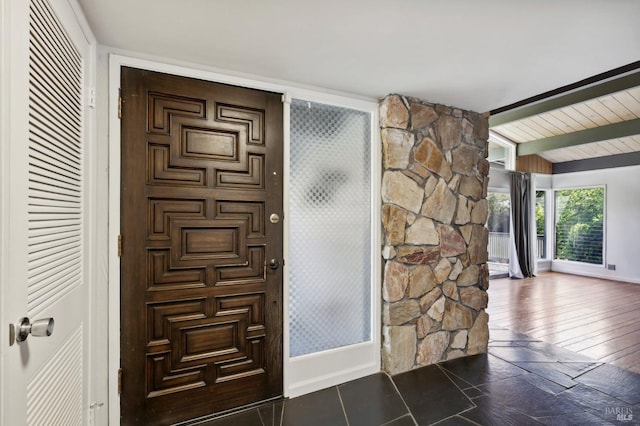 foyer entrance featuring dark hardwood / wood-style flooring and lofted ceiling with beams