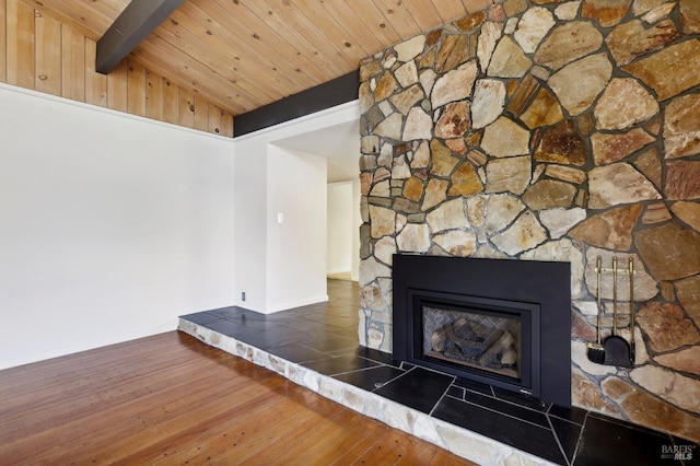 interior details with a glass covered fireplace, wood finished floors, wooden ceiling, and beamed ceiling