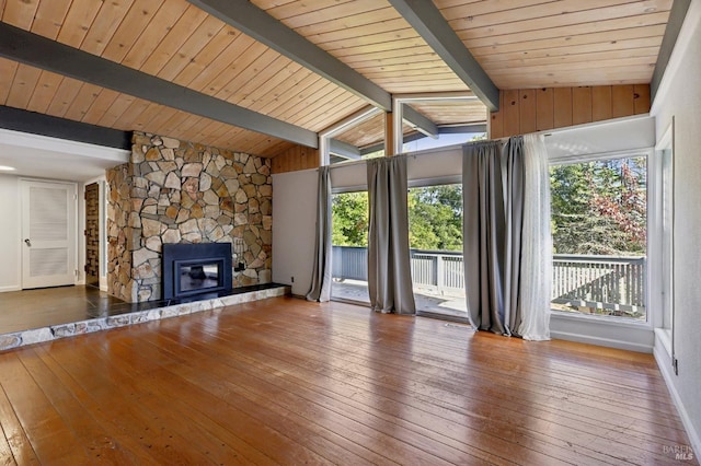 unfurnished living room featuring hardwood / wood-style flooring, vaulted ceiling with beams, a stone fireplace, and wooden ceiling