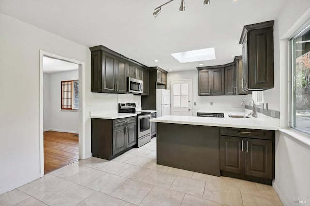 kitchen with a skylight, a wealth of natural light, stainless steel appliances, and light wood-type flooring