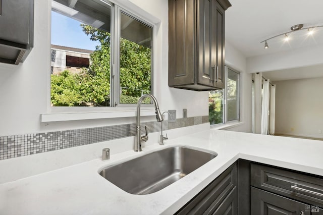 kitchen with decorative backsplash, dark brown cabinetry, sink, and a wealth of natural light