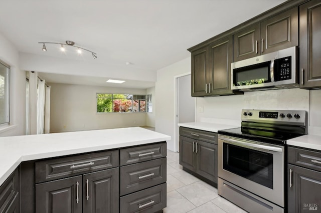 kitchen featuring kitchen peninsula, light tile patterned floors, dark brown cabinetry, and stainless steel appliances