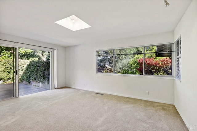 carpeted spare room featuring a skylight