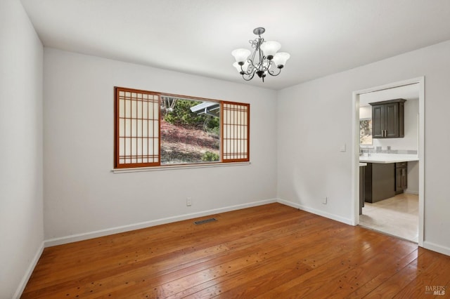 empty room featuring light hardwood / wood-style floors and a notable chandelier