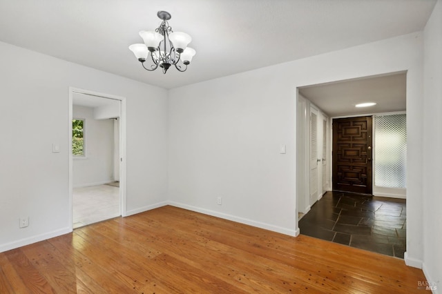 spare room with dark hardwood / wood-style flooring and a chandelier