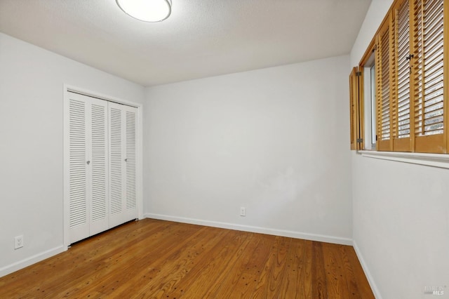 unfurnished bedroom with baseboards, a closet, and wood finished floors