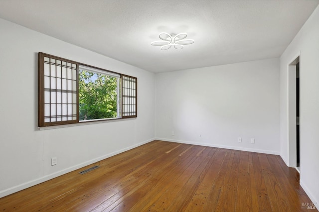 spare room with a textured ceiling and dark wood-type flooring