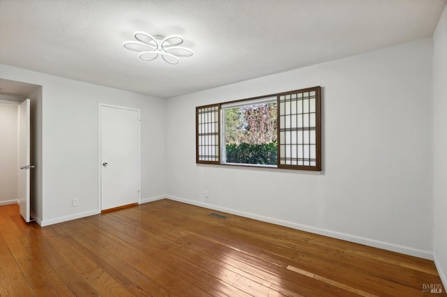 spare room featuring a textured ceiling and hardwood / wood-style flooring