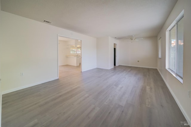 unfurnished room featuring hardwood / wood-style flooring, ceiling fan, and a textured ceiling