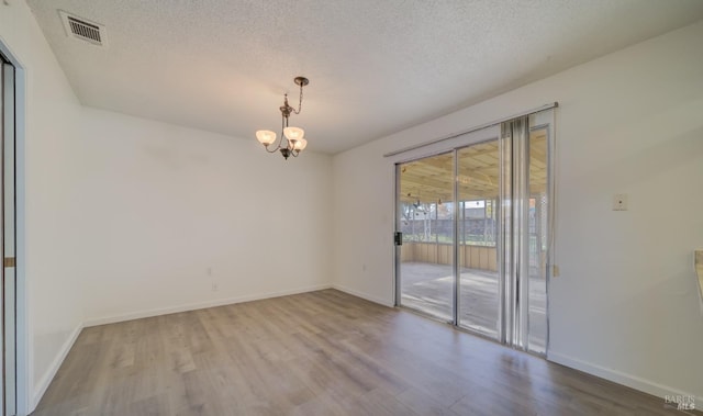 spare room featuring hardwood / wood-style flooring, a textured ceiling, and a chandelier