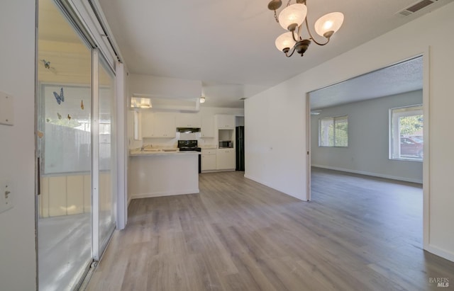 interior space featuring sink, white cabinetry, a chandelier, hanging light fixtures, and light hardwood / wood-style floors